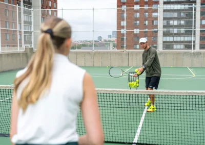 Coach providing training to a tennis player on the court.