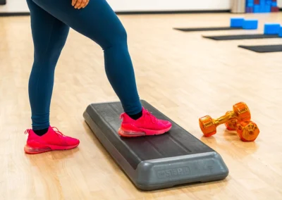 Women stepping on aerobic platforms with weights positioned on the floor.